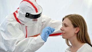 A traveller gets her swab sample collected in a Covid-19 walk-in test centre in Cologne, Germany, 08 August 2020.