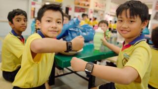 Дети в средней школе Адмиралтейства в Сингапуре демонстрируют свои новые платежные браслеты