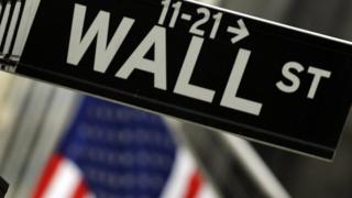 Sign for Wall Street with US flag in background