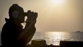 Soldado a bordo del buque destructor estadounidense USS Stethem mirando a la distancia con binoculares