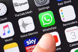 Dedo señala el icono del WhatsApp en la pantalla de un celular.