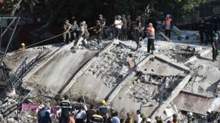 Rescuers and volunteers remove rubble and debris from a flattened building in search of survivors after a powerful quake in Mexico City on September 19, 2017.