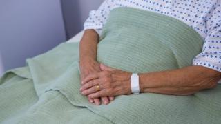 Old person's hands on hospital bed