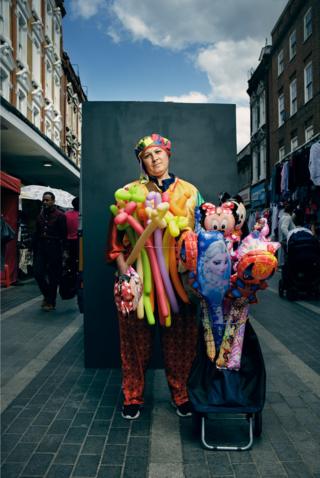Portrait of a person in the street holding balloons