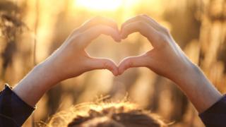 Mujer formando un corazón con sus manos.