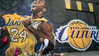 A man lights a candle in front of a Kobe Bryant mural in downtown Los Angeles on 26 January 2020