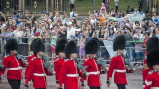 Tourists outside Buckingham Palace watching as guardsmen take part in the Changing of the Guard in central London