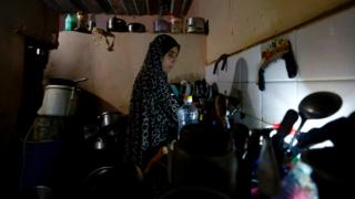 A Palestinian woman cleans the dishes using an LED lamp during a blackout in Gaza City on 20 June 2017