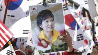 Сторонник президента Южной Кореи Пак Кын Хе держит свой портрет во время митинга против импичмента в Сеуле, Южная Корея, в пятницу, 10 марта 2017 года