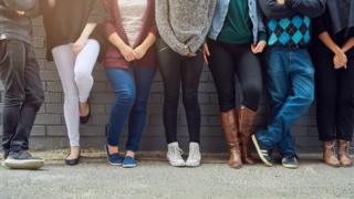 Jóvenes recostados en una pared
