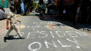 A policeman walks past a street sign by an RWA in a Delhi colony