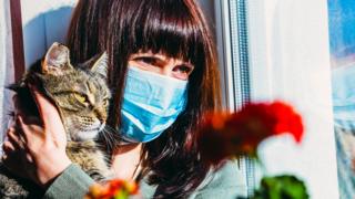 A woman with a cat in a protective mask