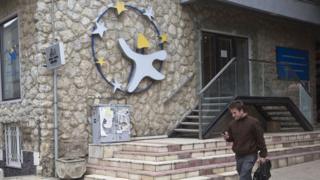 A Kosovar checks his mobile phone as he walks past EU Information and Cultural Office in Kosovo's capital Pristina