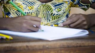 An girl at a desk in Africa drawing - stock image