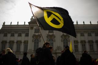 Protestor waves a flag with the logo of Generation Identity in front of the Justice Ministry. Vienna, April 2019