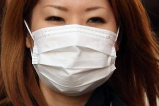 A woman wearing a mask walks past about the outbreak of coronavirus in Wuhan, China at Ginza shopping district in Tokyo, Japan, January 26, 2020. (Photo by Hitoshi Yamada/NurPhoto via Getty Images)