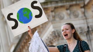 A student carrying a placard saying SOS