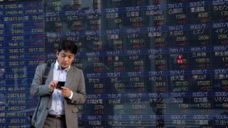 Man stands in front of stock boards in Japan