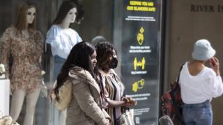 Shoppers, one wearing a mask