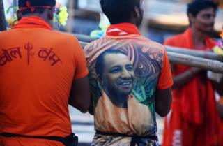 Индийский мужчина в футболке с фотографией главного министра штата Уттар-Прадеш Йоги Адитьянатха на спине