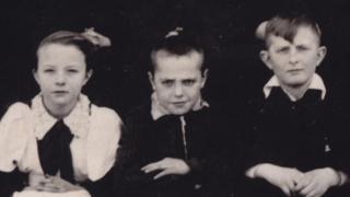 Tres niños en una foto antigua, en blanco y negro