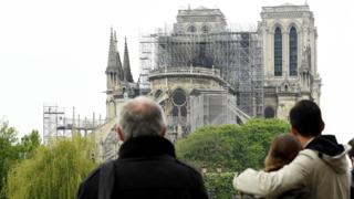 People hug while looking at Notre-Dame on 16 April 2019