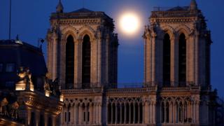 Der rosa Supermoon erhebt sich zwischen den beiden Türmen der Kathedrale Notre Dame