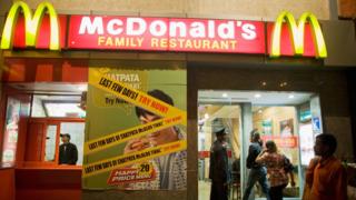 24 февраля 2009 года в Нью-Дели, Индия, охранник открывает дверь для клиентов в McDonalds на Рынке Хана.