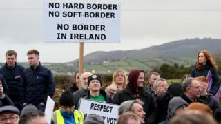 Brexit activists hold placards as they attend a demonstration by the anit-brexit campaign group 'Border communities against Brexit', a road crossing the border between Northern Ireland and Ireland in Newry, Northern Ireland, on January 26, 2019