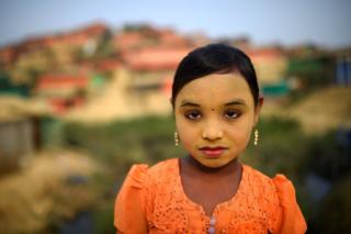   Zannat Ara, Rohingya refugee, 9, poses for a photo while she is carrying thanaka paste at Kutupalong Camp at Cox's Bazaar, Bangladesh 