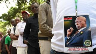 A man wearing a badge with the photo of late former Kenya"s President Daniel Arap Moi, queues to view his remains