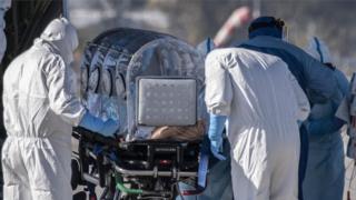 Medical workers move a patient with Covid-19 by plane