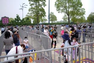 Visitors wearing face masks line up to enter the Shanghai Disneyland theme park