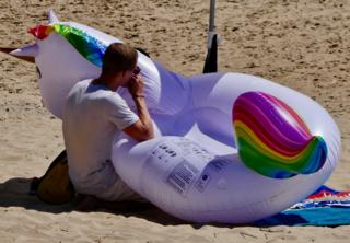 A man blows up an inflatable on a beach in Bournemouth