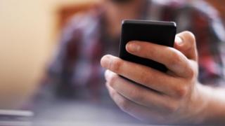 Una persona sosteniendo un teléfono en la mano