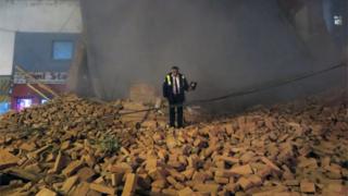 A policeman stands atop the rubble minutes after the collapse of the old Parravicini movie theatre building, in Tucuman, Argentina on May 23, 2018