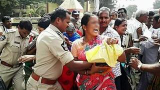 మహిళను నెడుతున్న పోలీసు