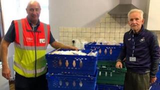 Менеджер Foodbank Mydrim Davies (справа) с водителем доставки Tesco и пожертвованной едой