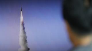 man watching missile test on TV