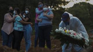 Relatives of a victim of the novel coronavirus disease Covid-19 mourn as their loved one is buried at the Vila Formosa cemetery in Sao Paulo