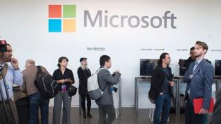 Peopel walk past a Microsoft sign