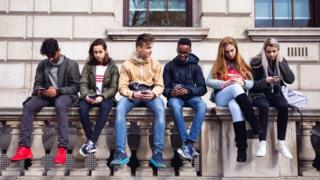Young people sat on a wall