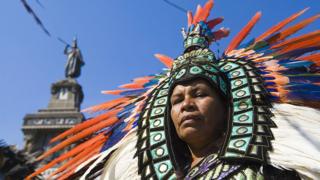 Una mujer vestida con un traje azteca