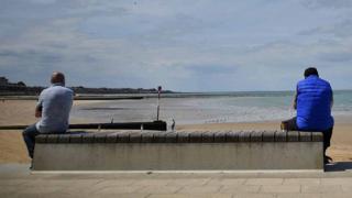 People social distance as the look towards Margate Sands beach in Margate south east England, on May 16, 2020