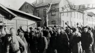 Survivors of Auschwitz leave through the infamous gates of Auschwitz I after the liberation