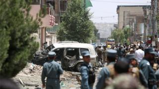 In this Friday, Aug. 7, 2015, photo, Afghan security personal inspect at the site of a suicide car bomber has targeted a NATO convoy in Kabul, Afghanistan.