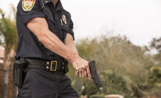 Policía sostiene una pistola.