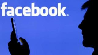 Un usager devant le logo de Facebook