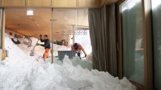 Workers clear snow from the Säntis hotel after an avalanche hit it in Schwägalp, Switzerland