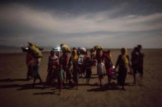 Un grupo de refugiados camina en la noche tras cruzar el río Naf, en su escape de la brutalidad del ejército de Birmania.